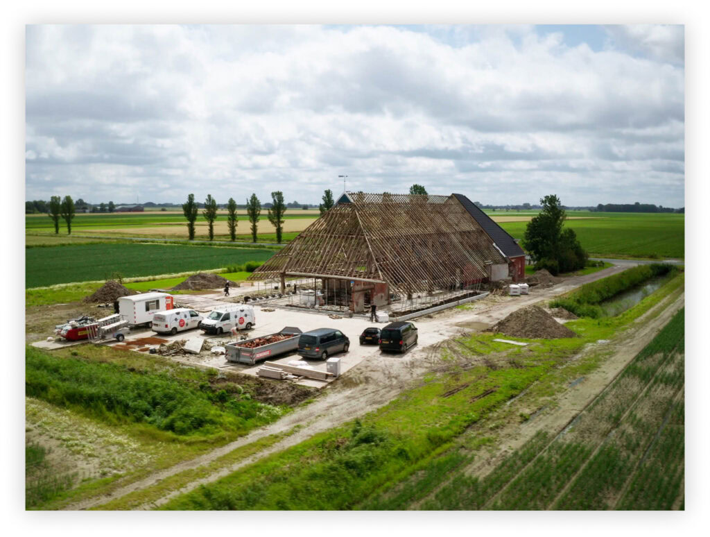 Vernieuwbouw van een boerenhuis met traditionele houten spanten op het platteland.