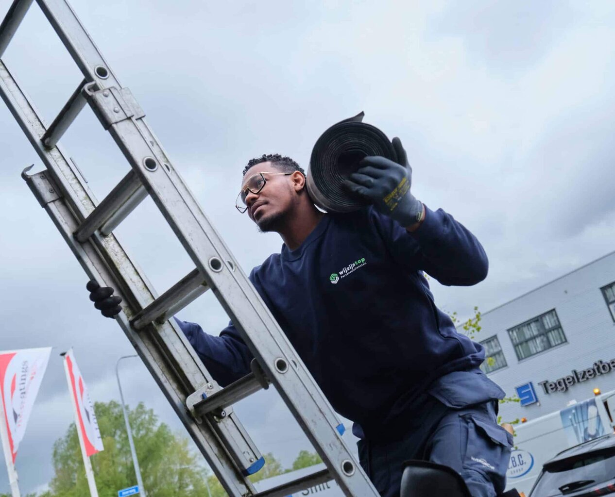 Ladderdrager medewerker voert werkzaamheden, bouwvakker transport equipment, professionele klusser in buitenomgeving.